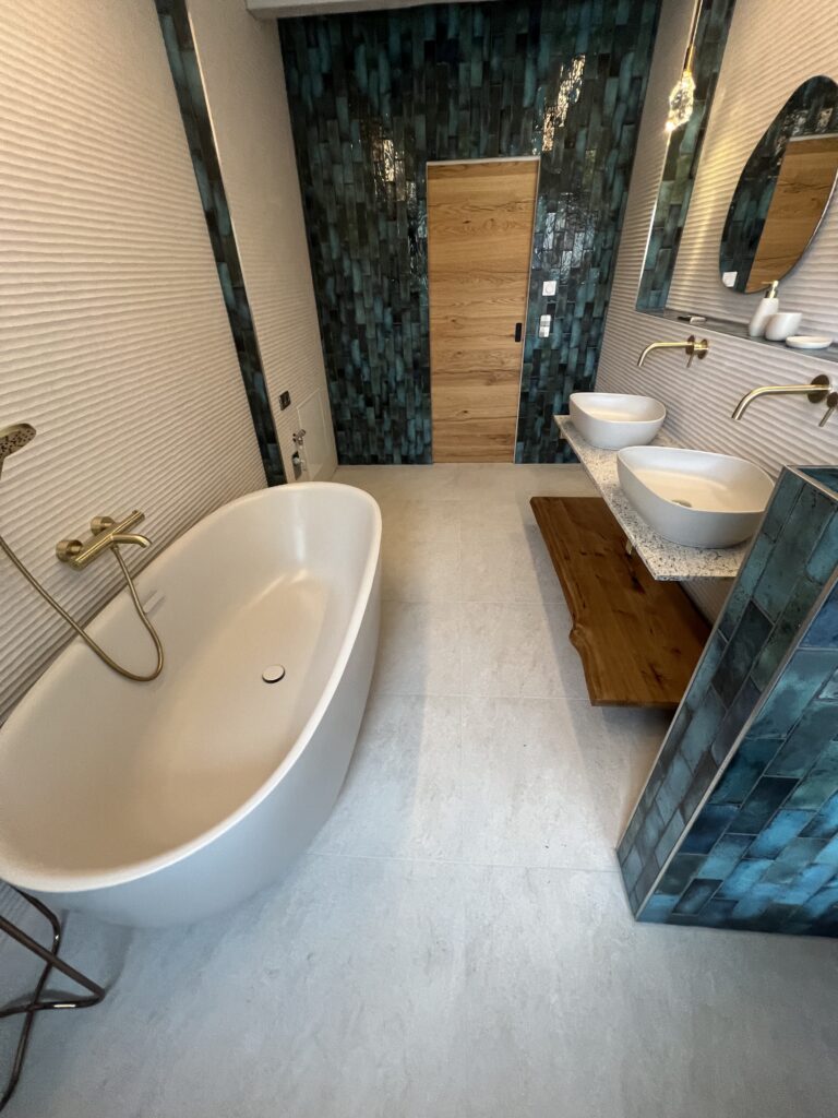 Modernes Badezimmer mit freistehender Badewanne, Doppelwaschtisch und türkis glasierten Fliesen – ideal für Badsanierung