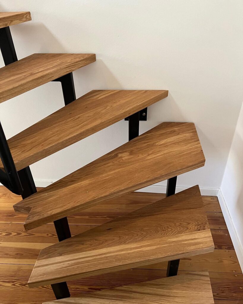 Holztreppe mit massiven Eichenstufen und schwarzer Metallunterkonstruktion, Treppenbau bei Bausanierung